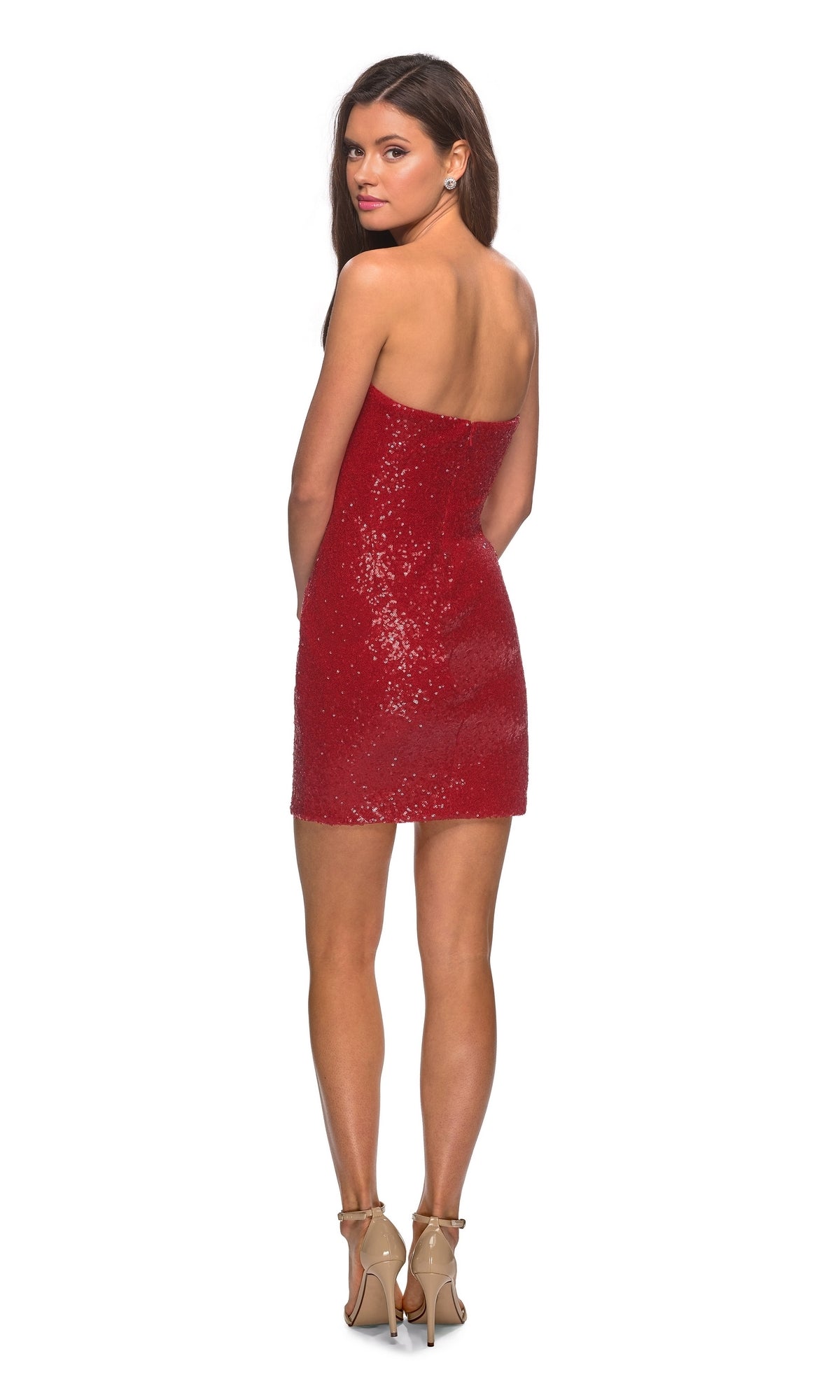 A woman wearing the La Femme Short Strapless Sequin Hoco Dress 28229 and beige high heels stands facing away, glancing over her shoulder against a plain white background.
